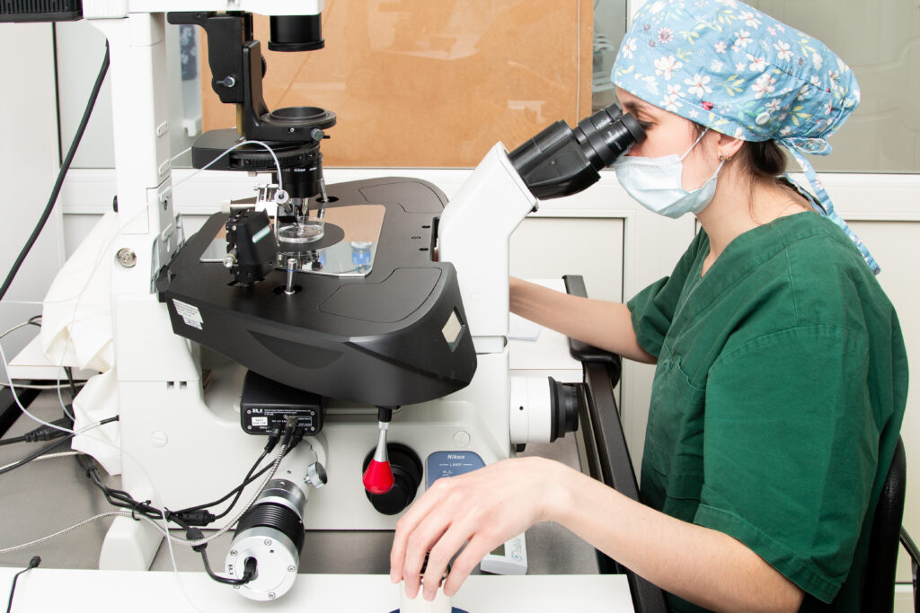 Elite Clinic 3 Medical professional in green scrubs working at a microscope in an IVF laboratory.