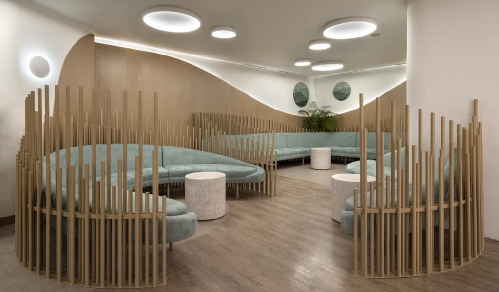 Spacious and contemporary waiting room with curved seating, soft lighting, and natural wood accents at Ovagenesis fertility clinic in Athens