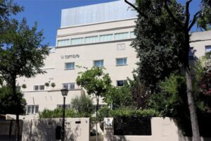 Soft-toned building of Clínica Tambre with trees and plants framing the entrance.